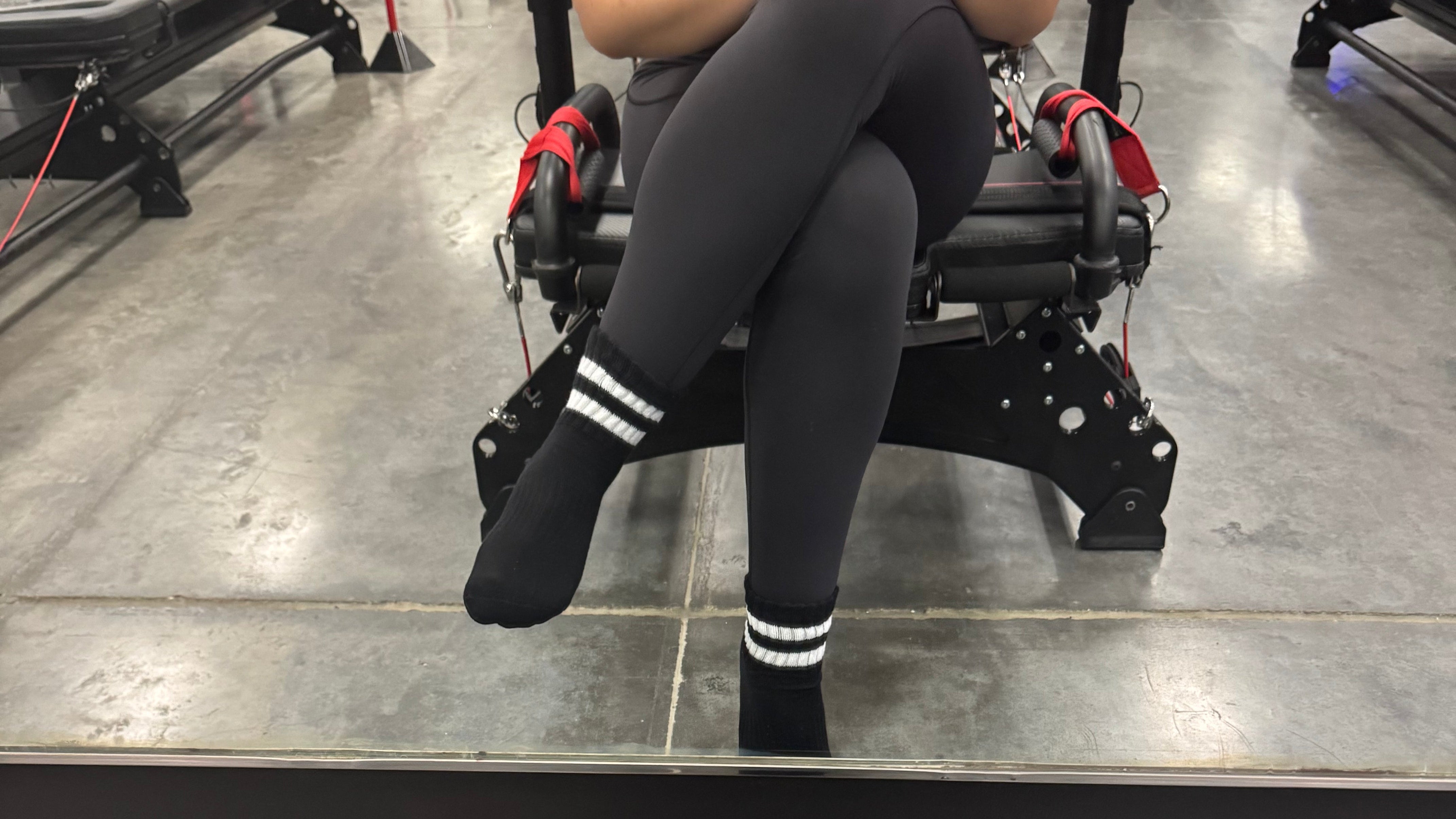 Person sitting on a chair with a mirror reflecting their legs and shoes on a table.